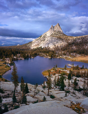  Cathedral Peak is illuminated in stormy  light above stormy Upper Cathedral Lake located in the Tuolumne Meadows section of Yosemite National Park.