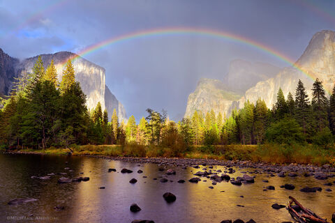 The Gates of the Valley view of Yosemite Valley is draped with a dramatic rainbow and mist, in Yosemite National Park.