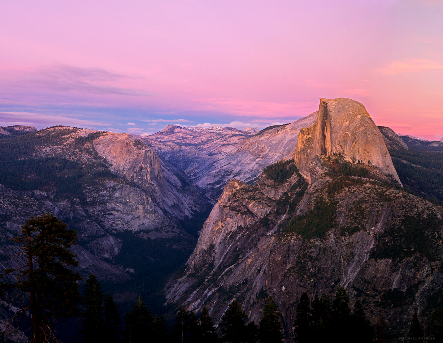 In Yosemite, half dome glows pink in alpenglow sunset light as seen from Glacier Point.