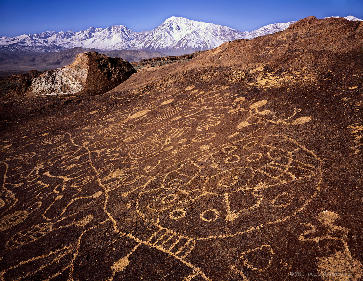 Native American petroglyphs, ancient writing full of culture and beauty, beneath the backdrop of the snow-capped Eastern Sierra Nevada range.