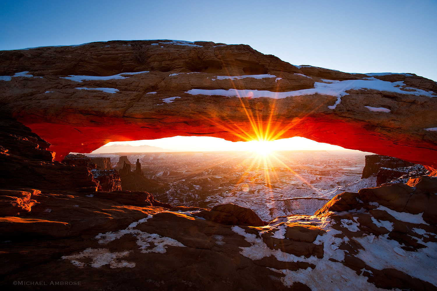 Mesa Arch, etched with snow,  glows with a starburst in Cayonlands National Park, in Utah.