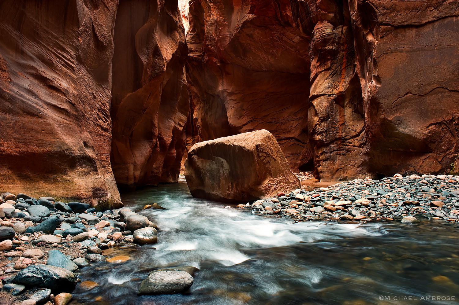 A river runs through a deep slot canyon in the narrows section of Zion National Park.